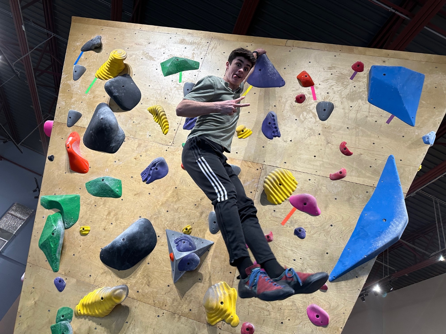 Young climber throwing a peace sign mid-climb