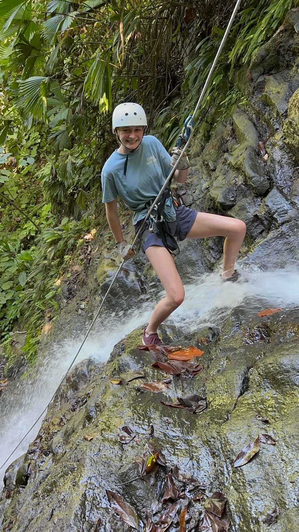 Young climber rappelling beside a waterfall